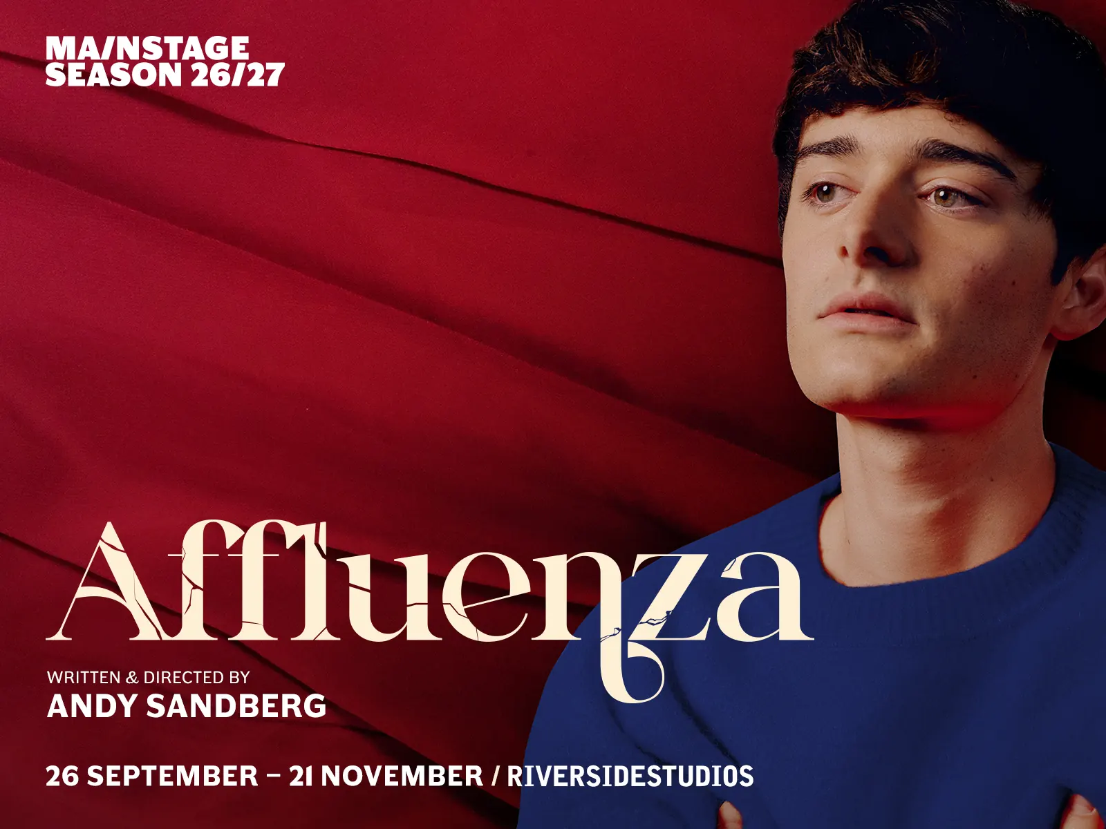 Man in blue shirt against red background in Affluenza at the Riverside Studios
