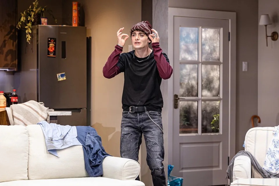 Noah Schnapp as Todd adjusts a cap in Affluenza at the Riverside Studios
