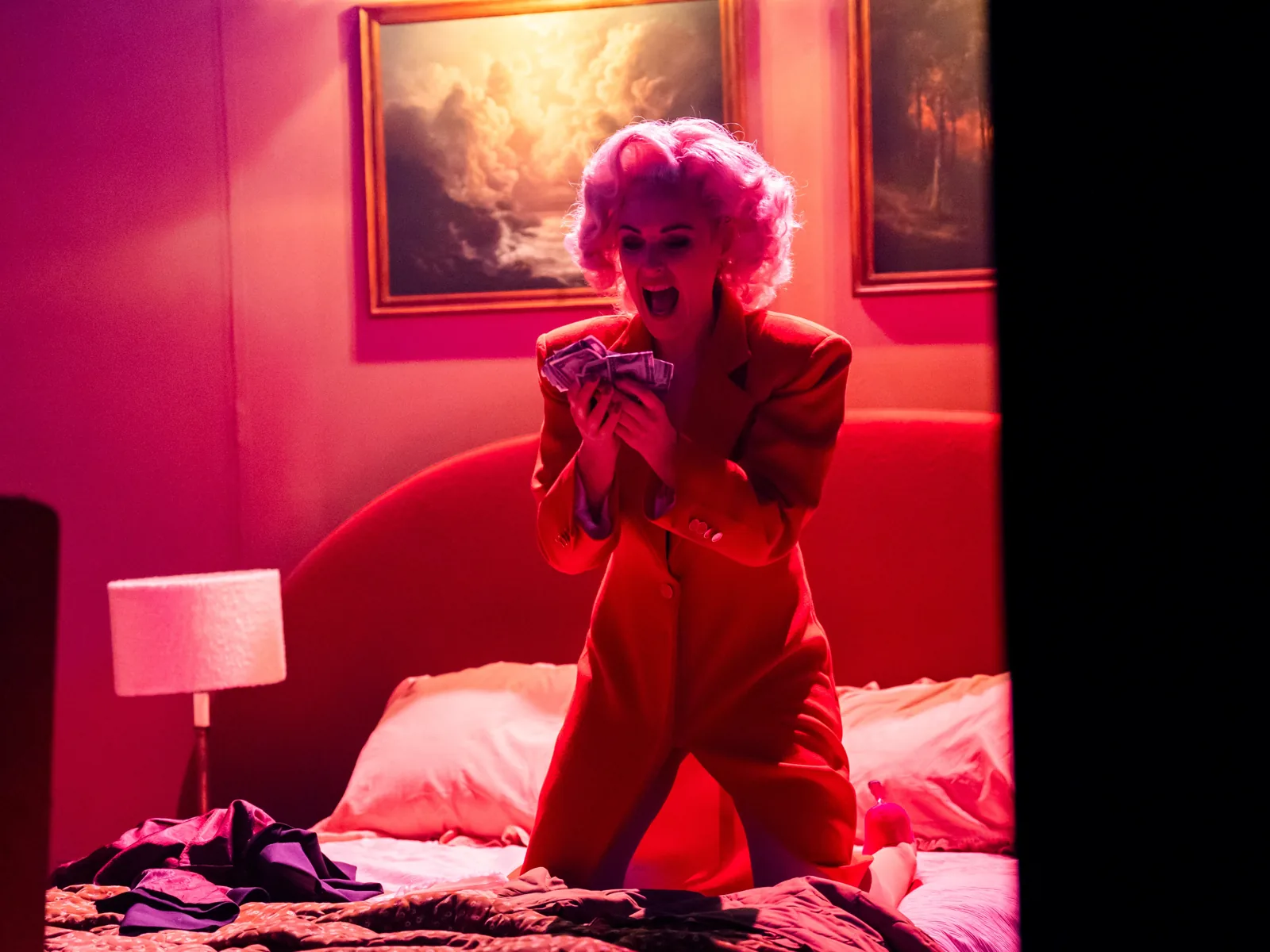 A singer in a red suit kneels on a bed, Angel's Bone, London Coliseum