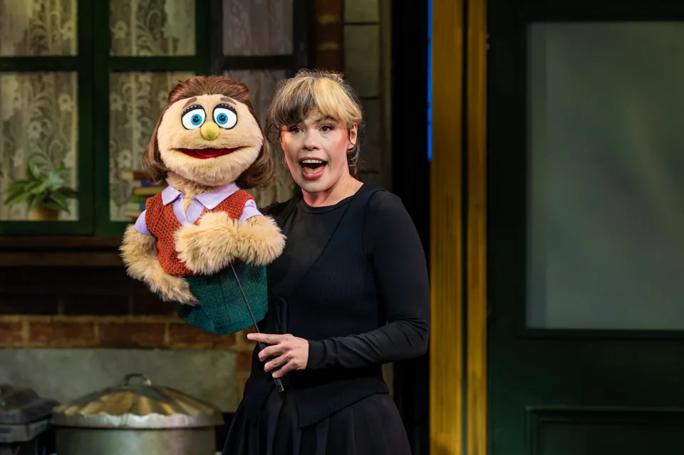 Emily Benjamin sings with a brown-haired puppet, Avenue Q at the Shaftesbury Theatre