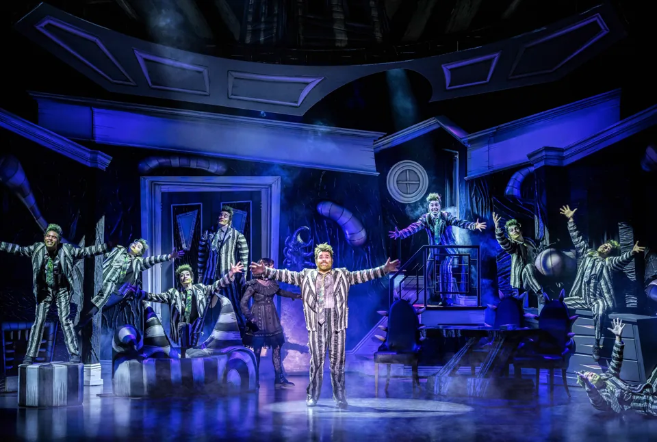 Dancers in black-and-white stripes leap around the haunted house set in Beetlejuice, Prince Edward Theatre