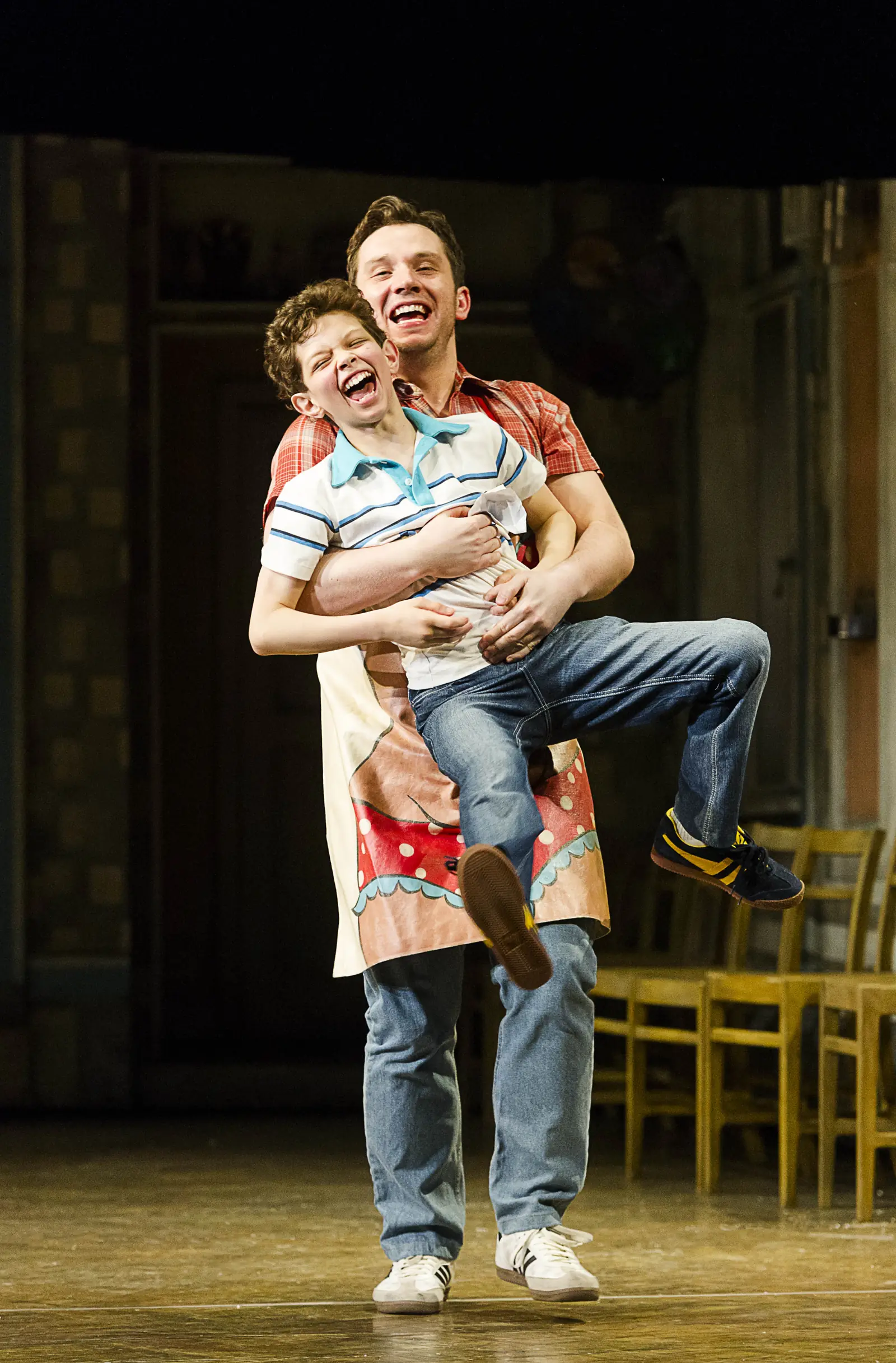 Tony lifts a laughing Billy off the ground in Billy Elliot the Musical