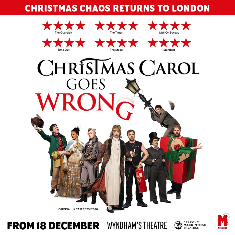 The Cornley company in costume beside a giant present, Christmas Carol Goes Wrong, Wyndham's Theatre