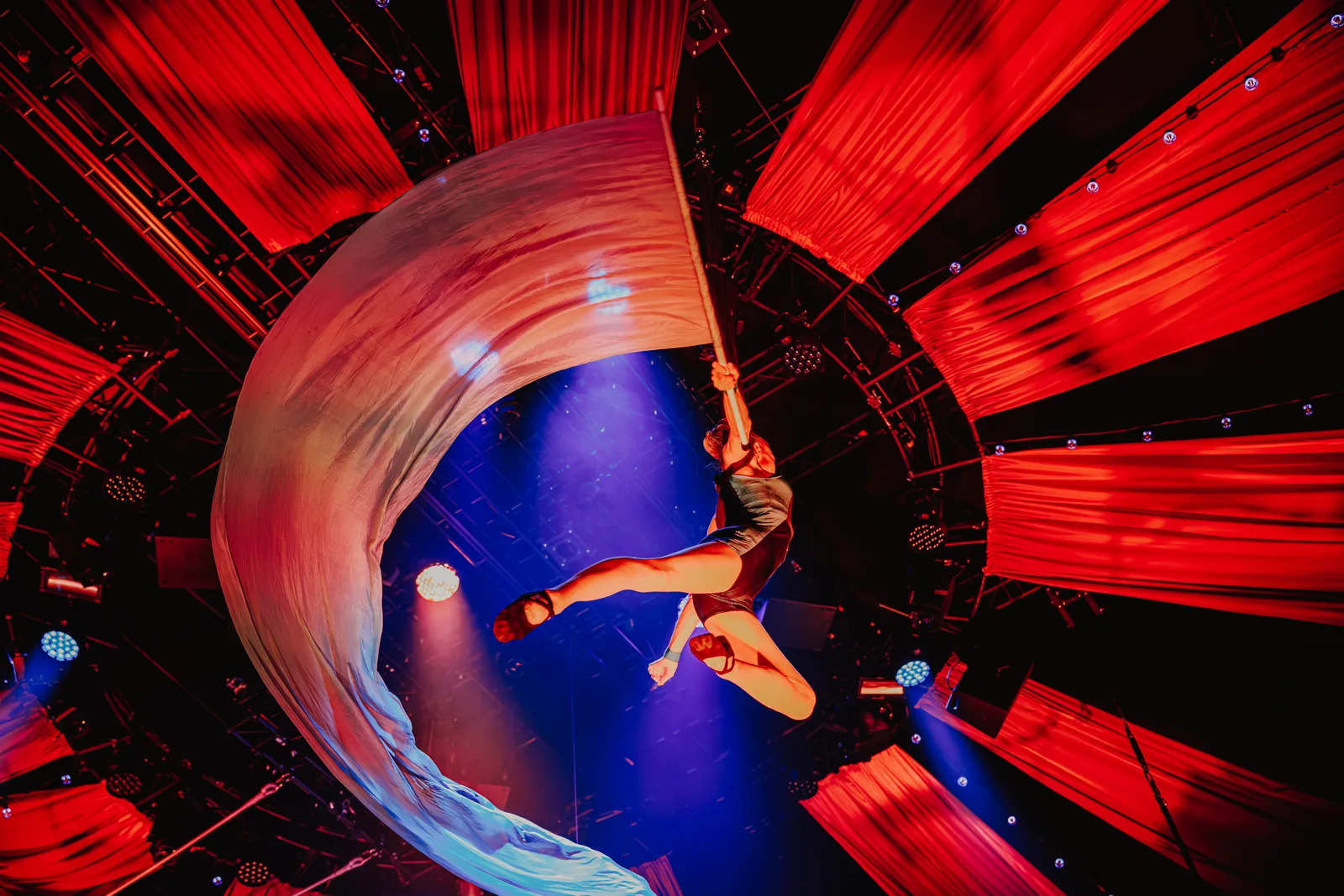An aerialist swings a long silk banner beneath red drapes, Come Alive!, Empress Museum