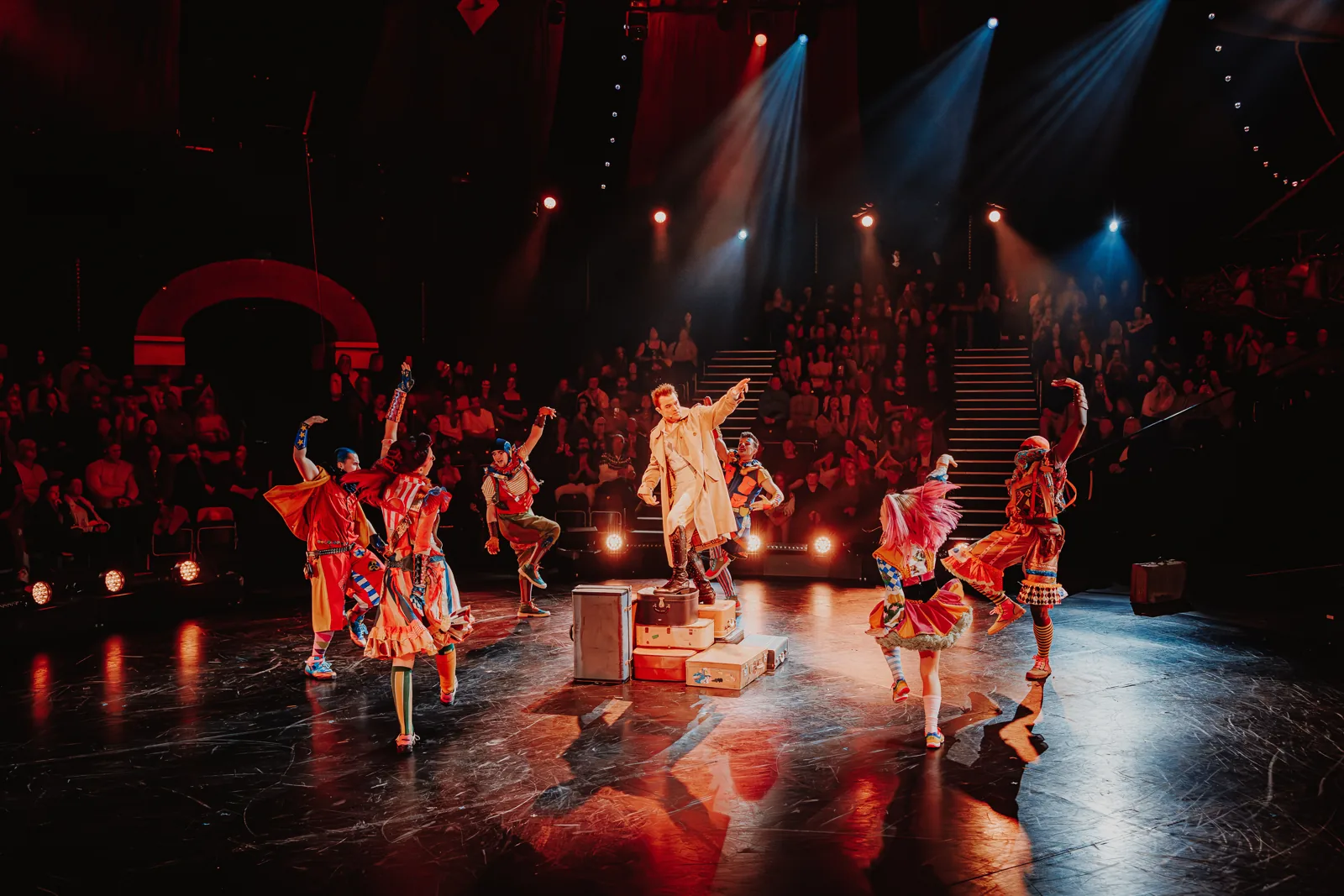 A performer on a suitcase leads dancers in bright costumes, Come Alive!, Empress Museum