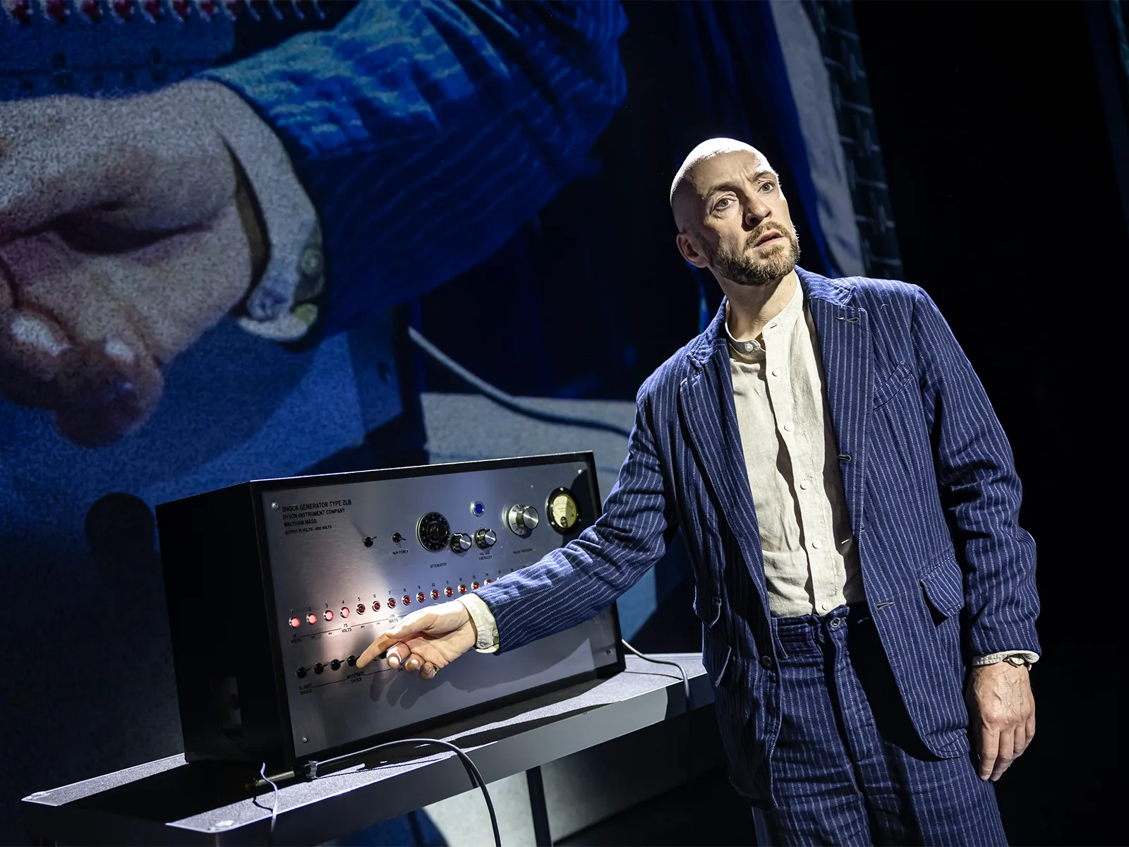 Derren Brown at a control box with a row of switches, Only Human at the Apollo Theatre