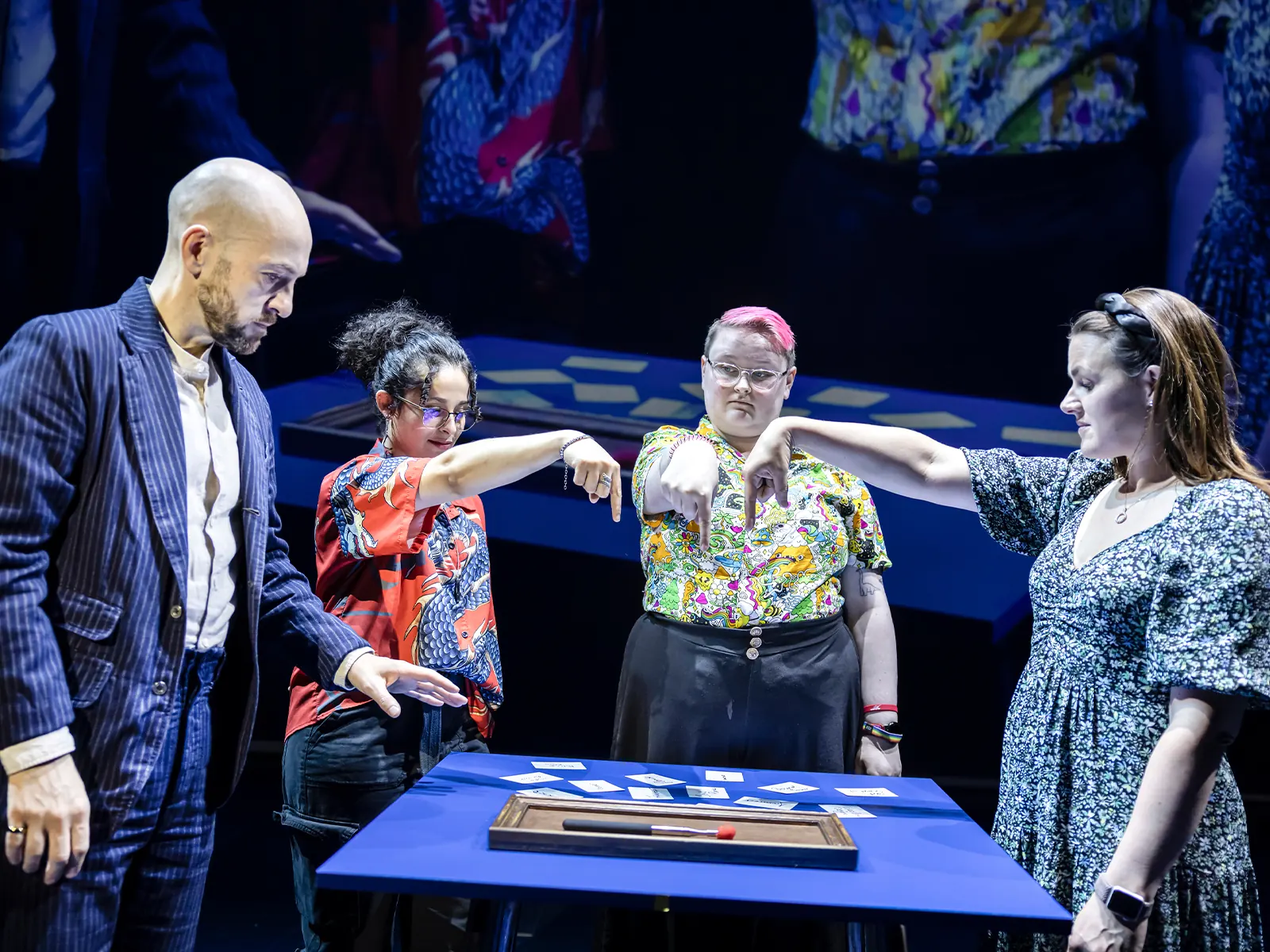 Derren Brown with four volunteers pointing at cards on a table, Only Human at the Apollo Theatre