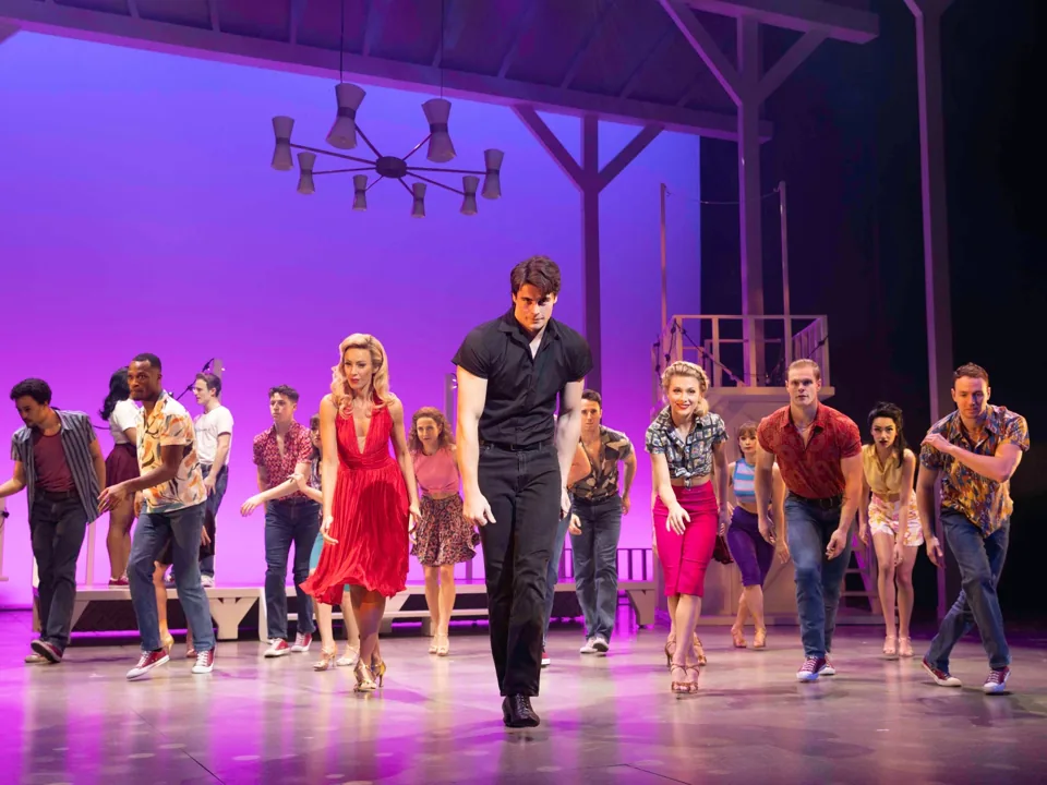 The company struts forward under purple light, Dirty Dancing at the Prince Edward Theatre