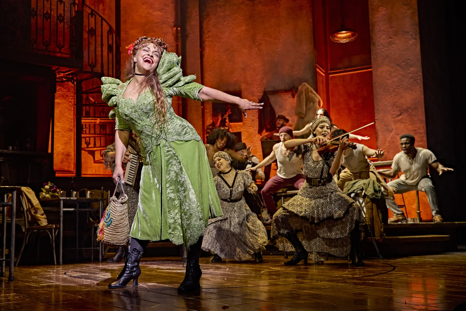 Danielle de Niese as Persephone with a fiddler and the company, Hadestown, Lyric Theatre