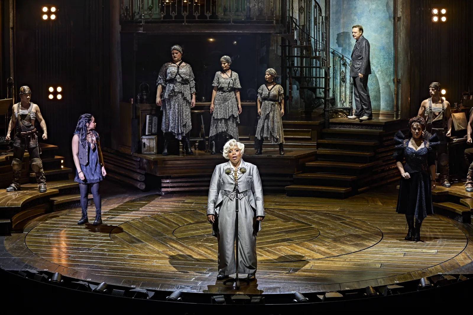 Malinda Parris as Hermes and the company on the round stage, Hadestown, Lyric Theatre