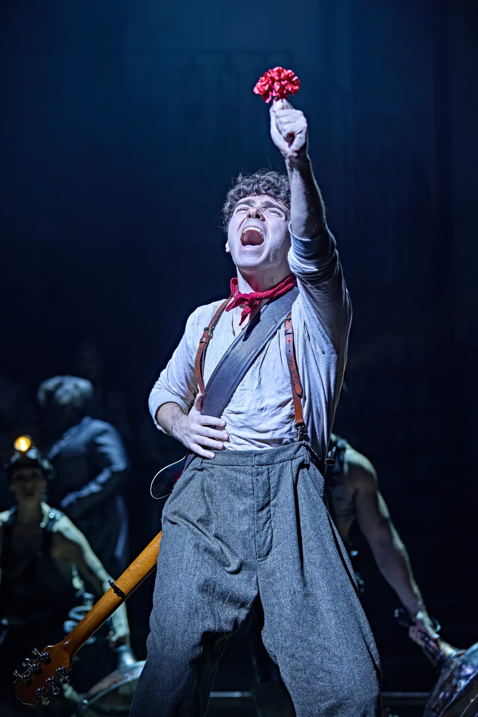 Nathan Sykes as Orpheus holds a red flower aloft and sings, Hadestown, Lyric Theatre