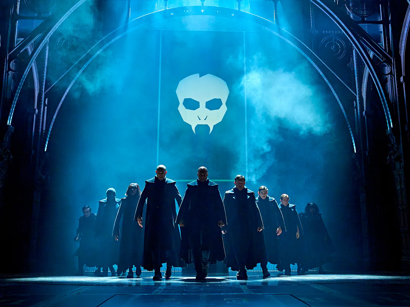 Dark-robed figures march under a glowing skull emblem, Cursed Child at the Palace Theatre