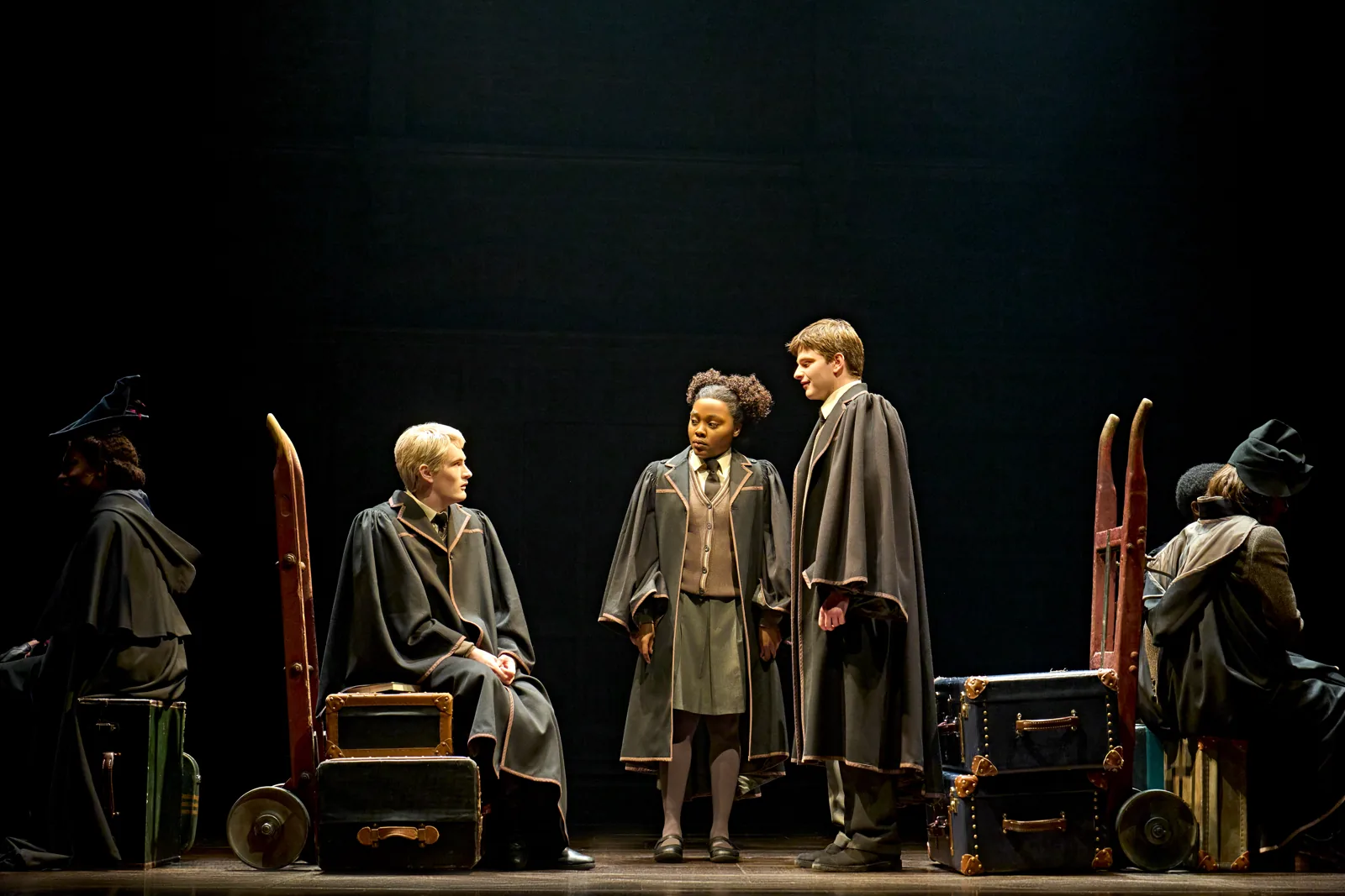 Scorpius, Rose and Albus in robes among trunks and trolleys, Cursed Child, Palace Theatre