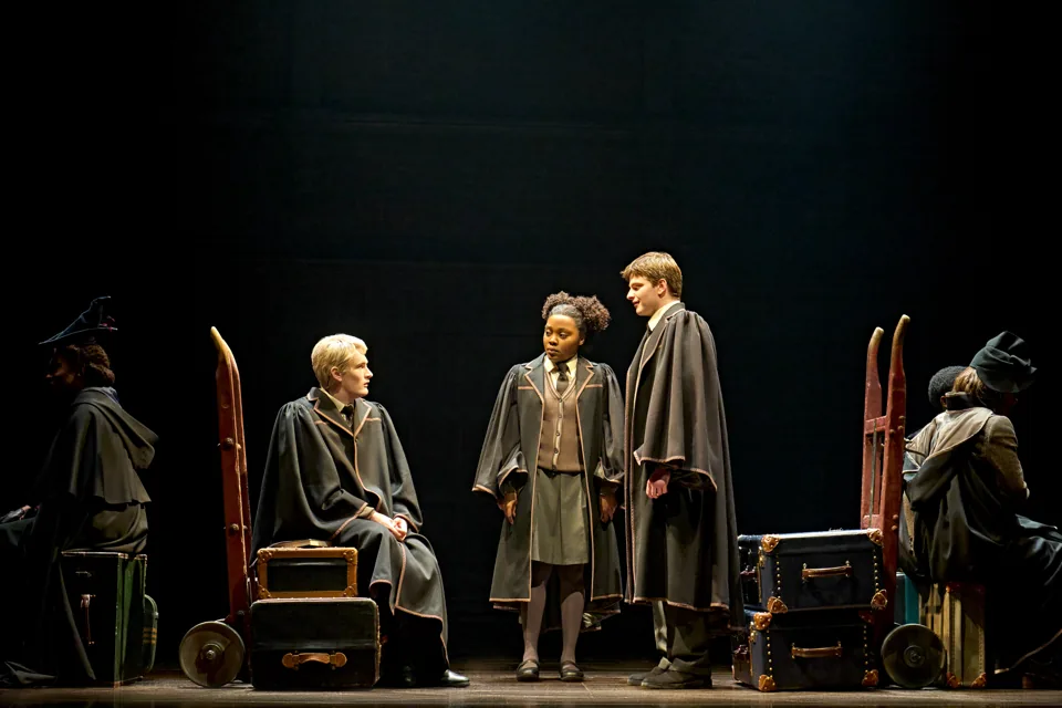 Scorpius, Rose and Albus in robes among trunks and trolleys, Cursed Child, Palace Theatre