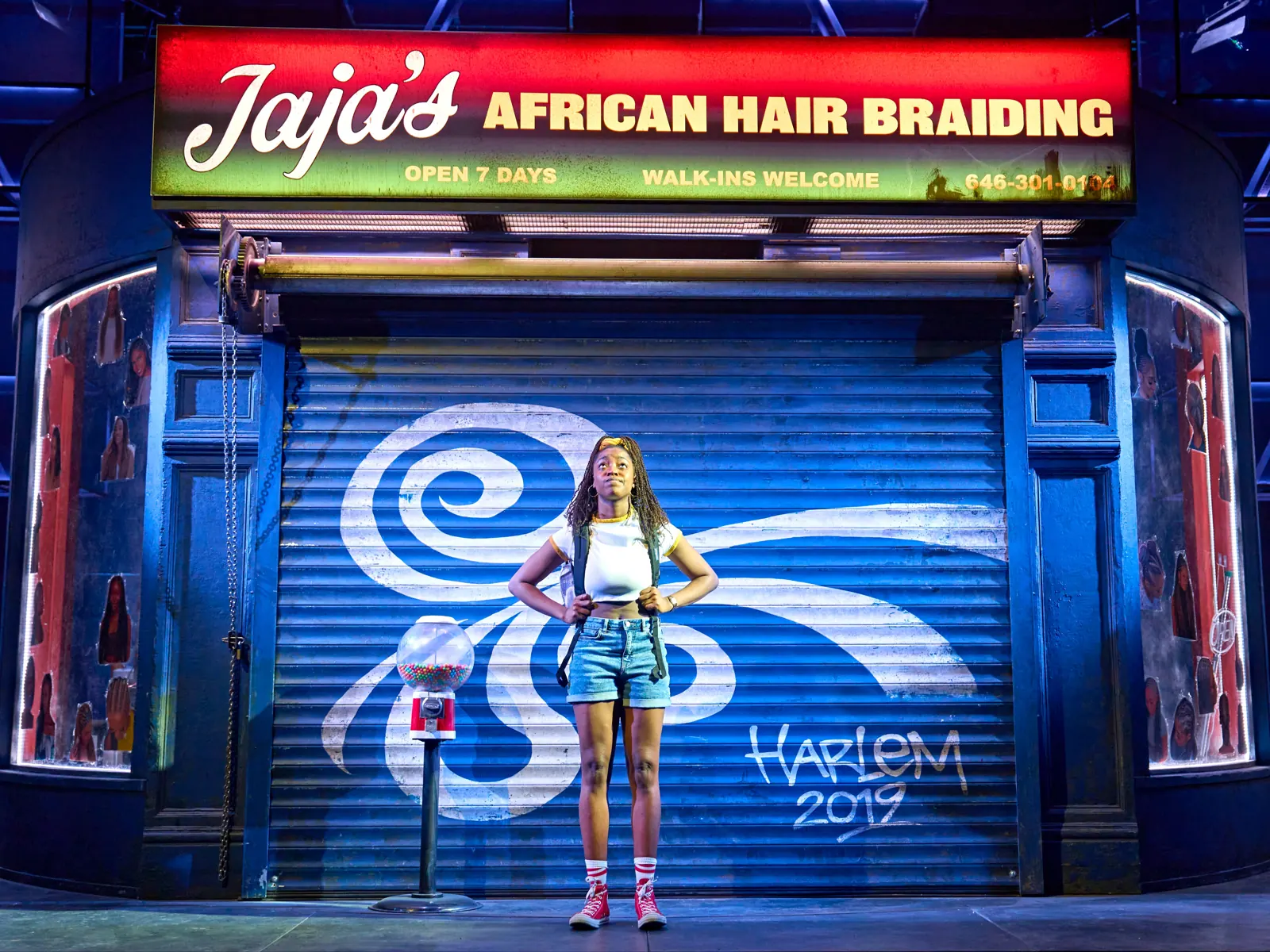 Sewa Zamba as Marie in front of the salon's shutter, Jaja's, Lyric Hammersmith