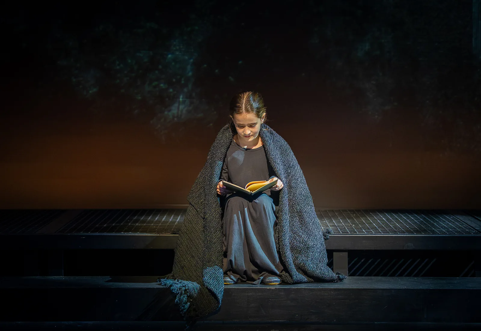 Young Jane reads alone under a grey blanket, Jane Eyre, Southwark Playhouse Elephant