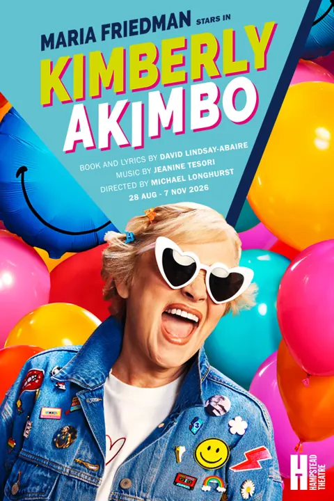 Person in heart-shaped sunglasses surrounded by balloons in Kimberly Akimbo at the Hampstead Theatre