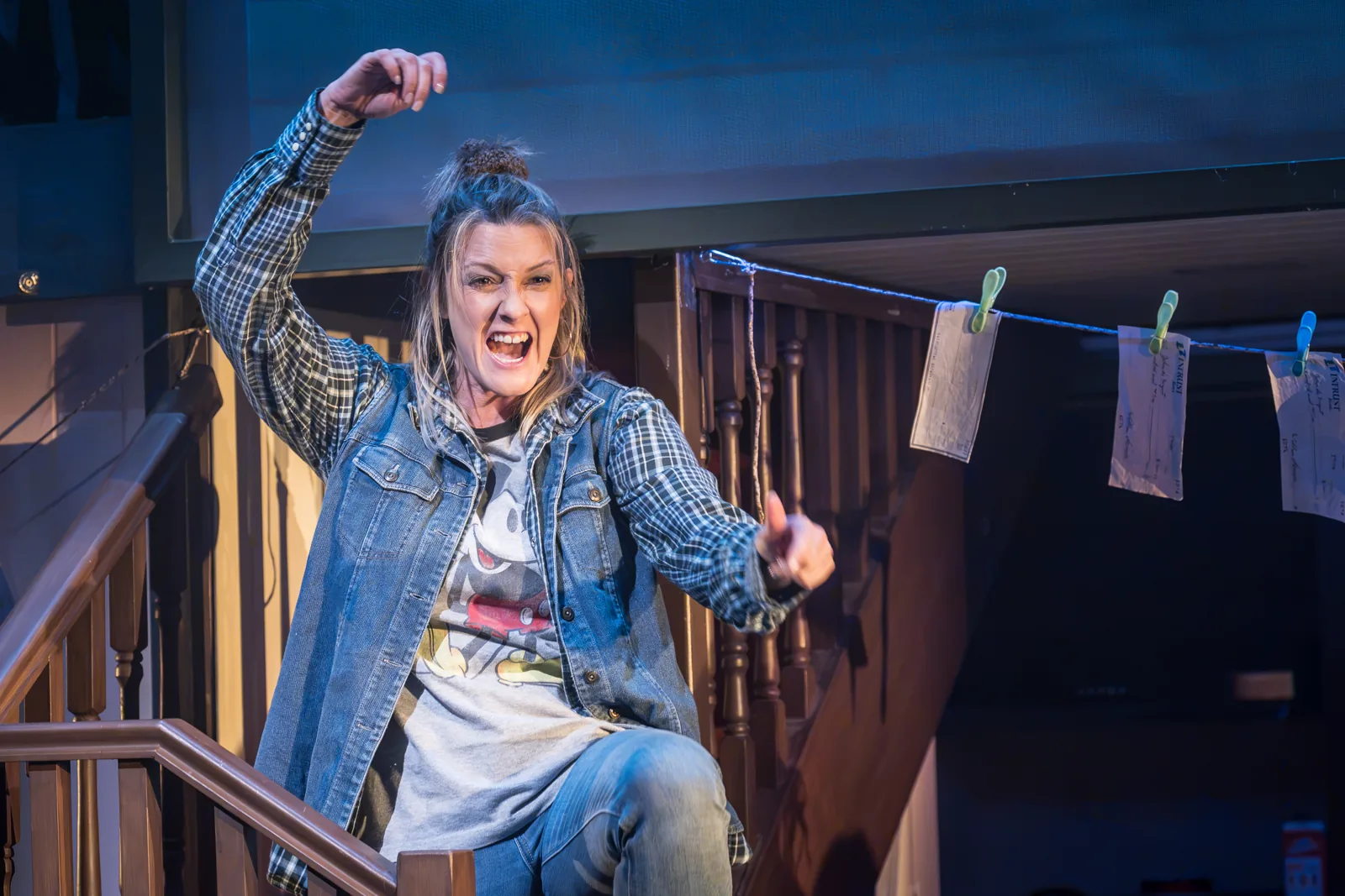 A woman in denim punches the air on the stairs in Kimberly Akimbo, Hampstead Theatre