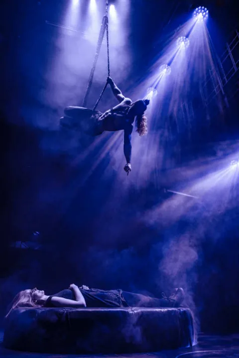 An aerialist hangs from straps above a bed, Magic Mike Live, Hippodrome Casino