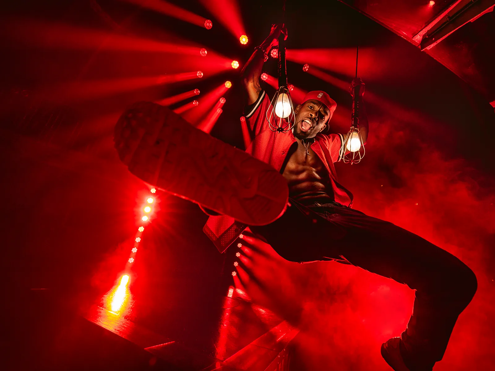 A dancer in a red cap leaps under red lights, Magic Mike Live, Hippodrome Casino