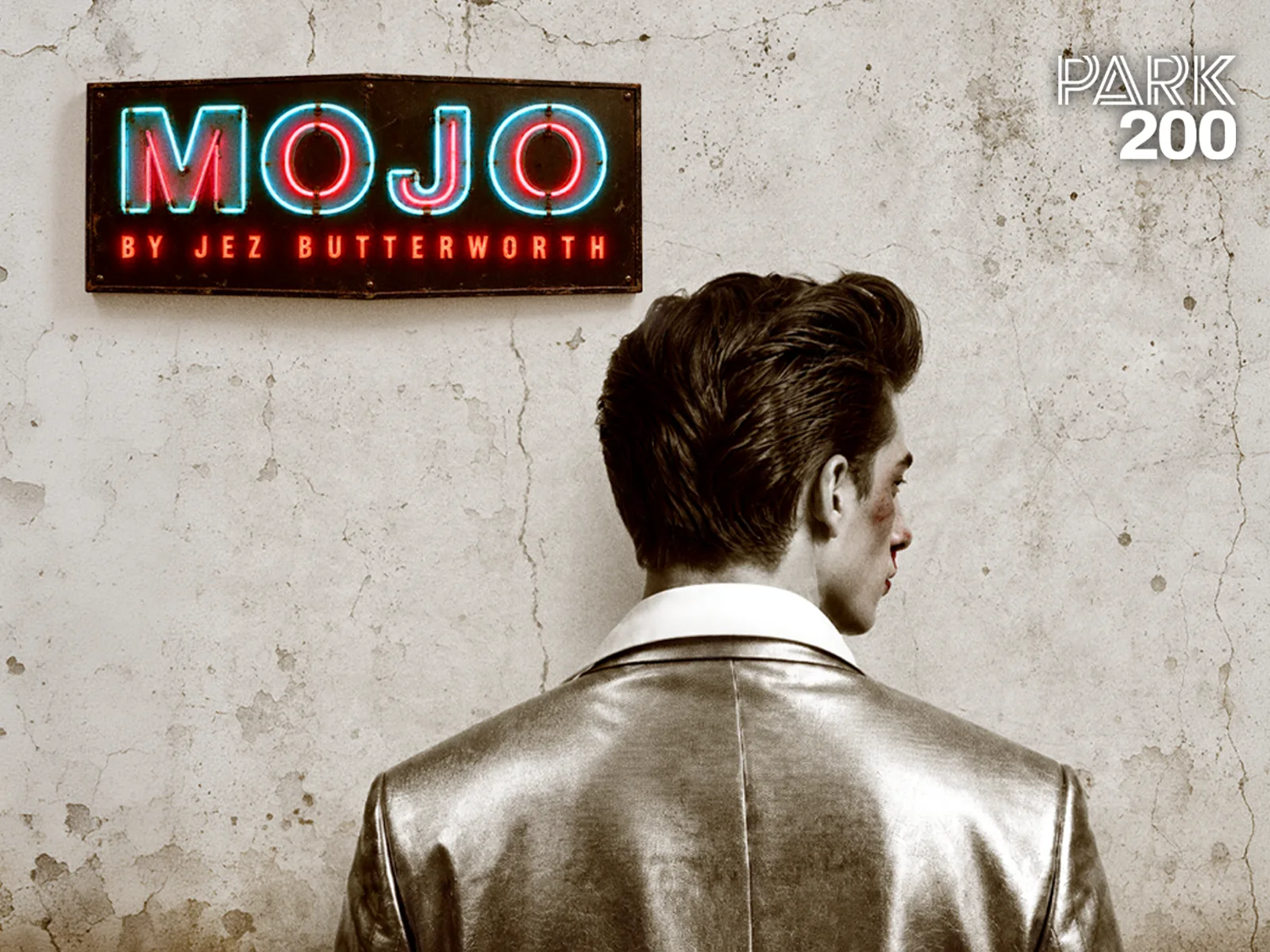 Mojo neon logo above man in silver jacket in Mojo at the Park Theatre
