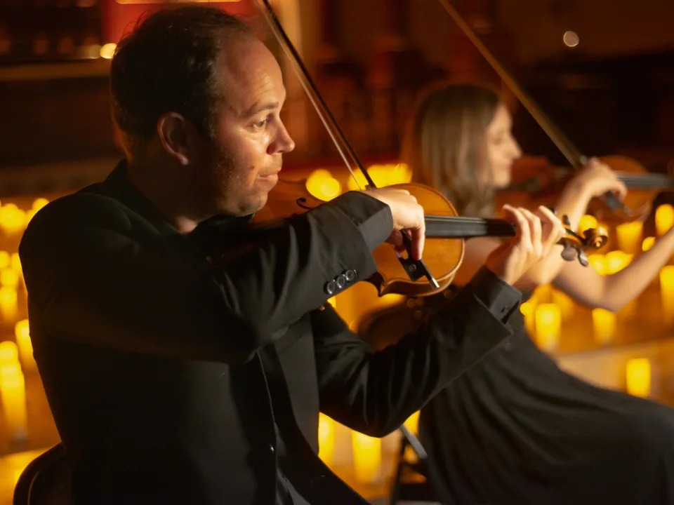 Two string players perform in warm candlelight at Musicals by Candlelight, The Actors' Church