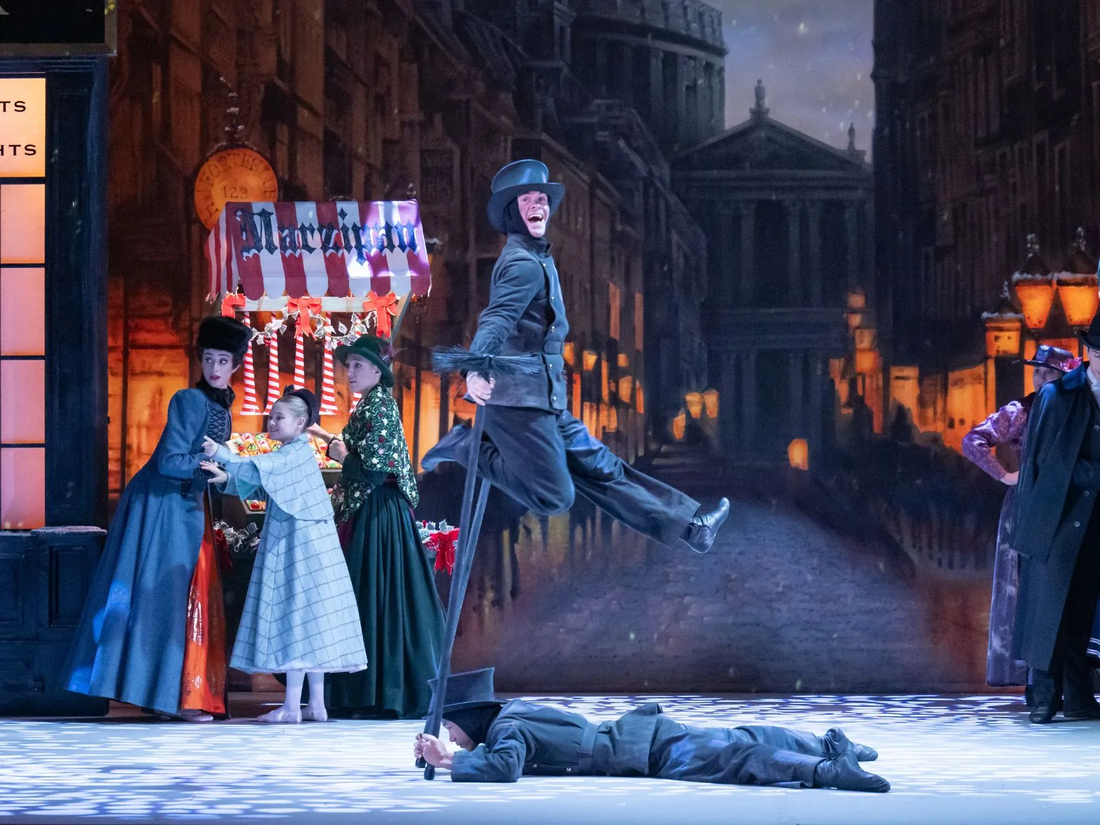 A dancer in a top hat leaps on a snowy street, Nutcracker, London Coliseum