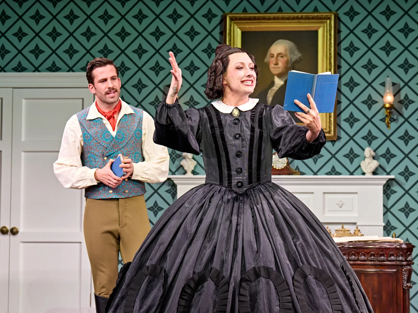 Mary Todd Lincoln flourishes a blue book beside her teacher in Oh, Mary!, Trafalgar Theatre