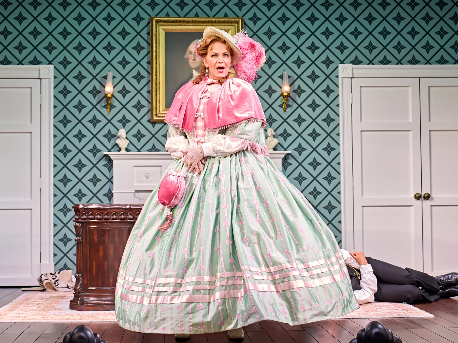 Mary's Chaperone in a pink cape and striped gown in Oh, Mary!, Trafalgar Theatre