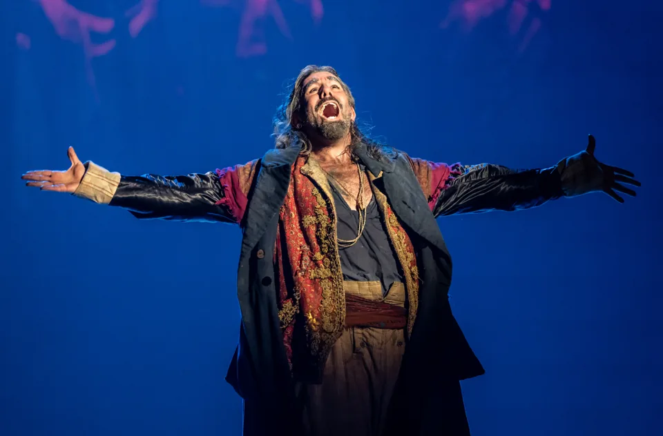 Fagin, arms flung wide, in Oliver! at the Gielgud Theatre