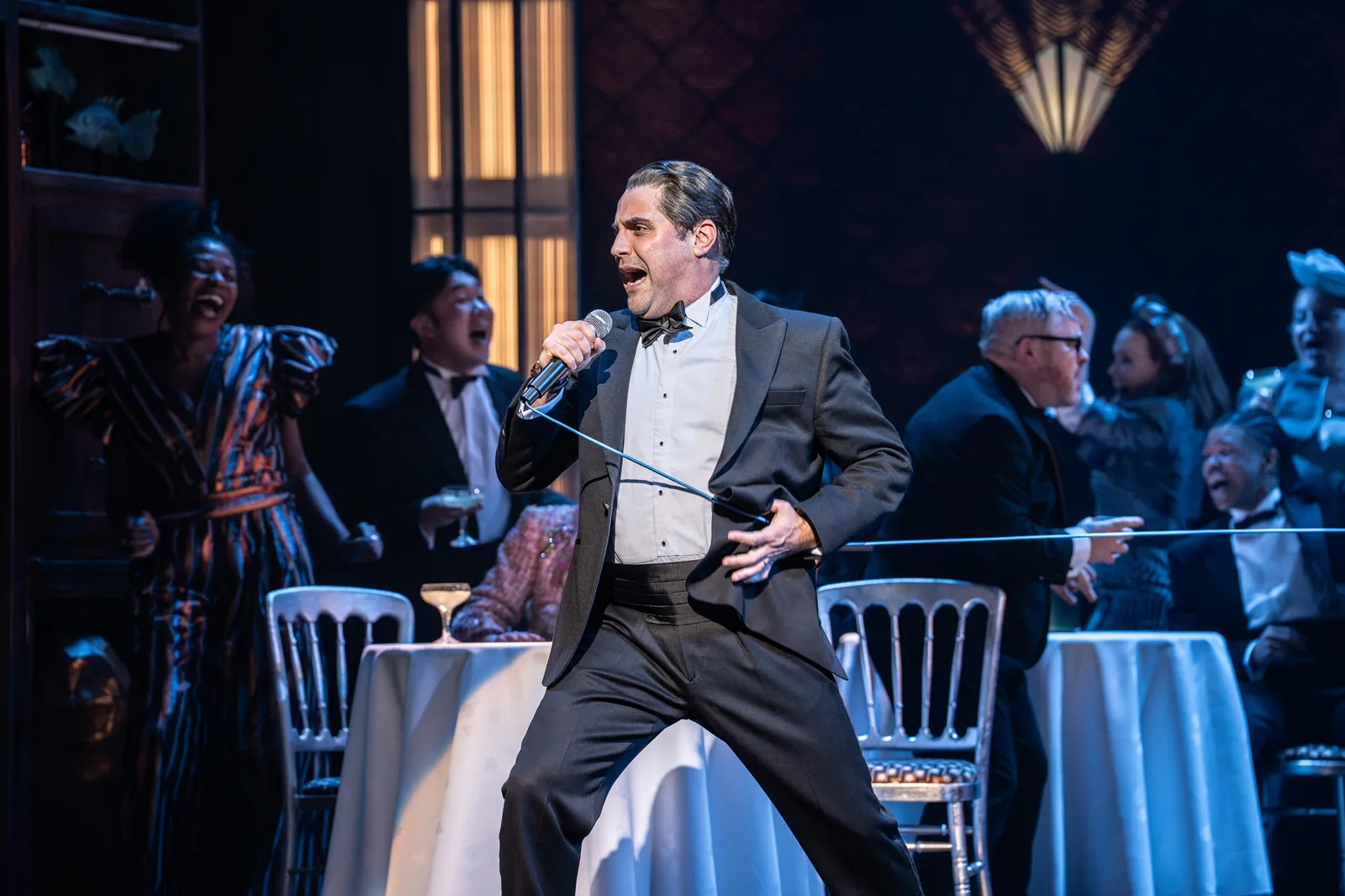 A man in a dinner jacket sings at a party, Paddington The Musical, Savoy Theatre