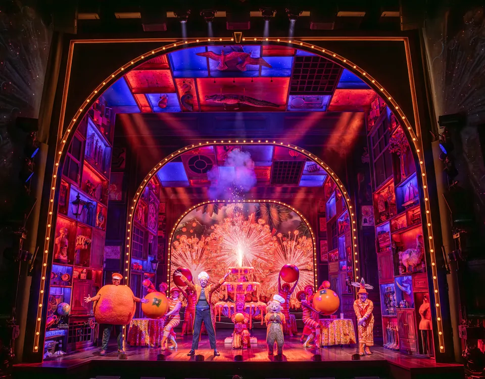 Giant oranges and sparks fill an arched stage in Paddington The Musical, Savoy Theatre