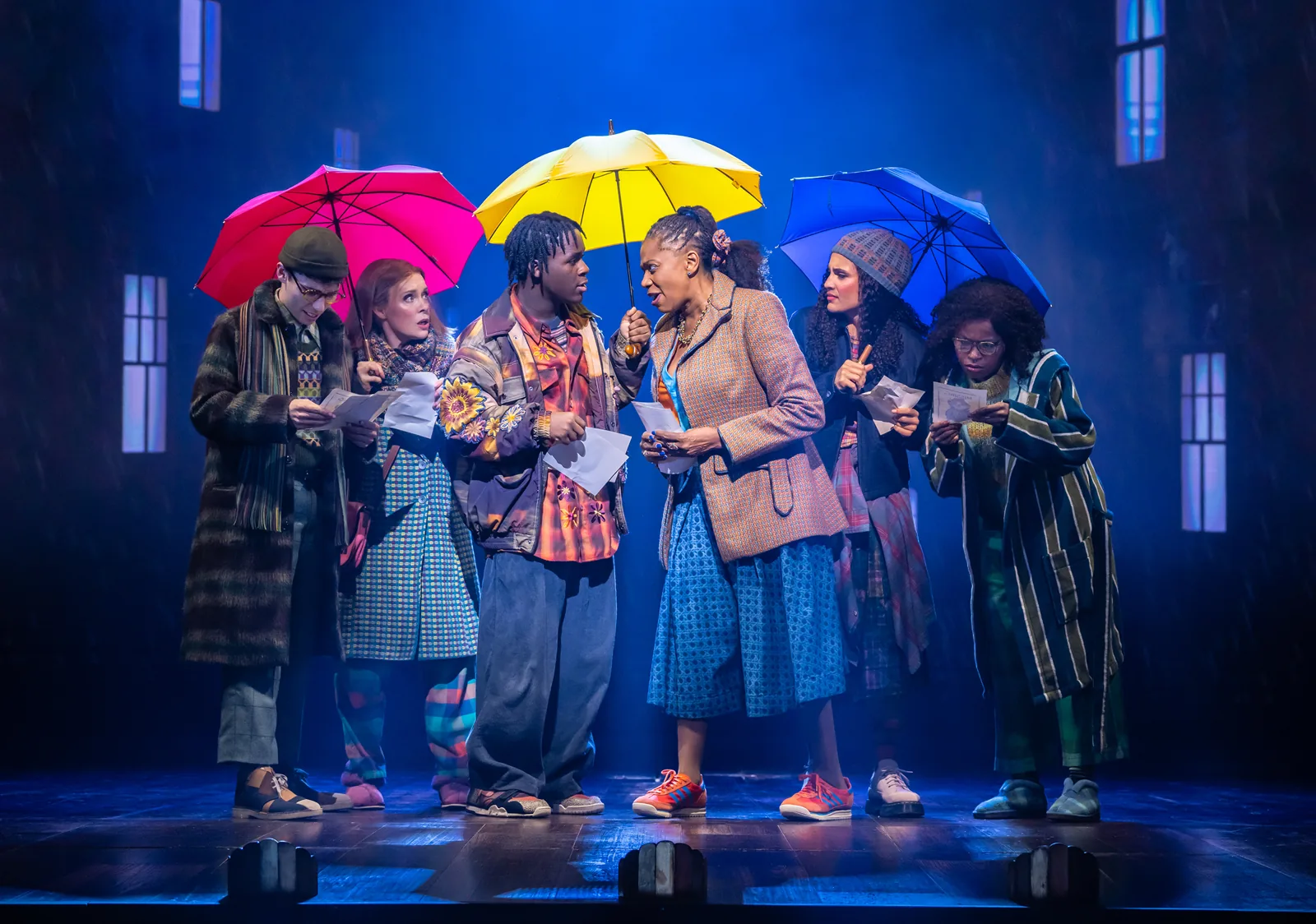 Neighbours read notes under bright umbrellas in the rain, Paddington The Musical, Savoy Theatre