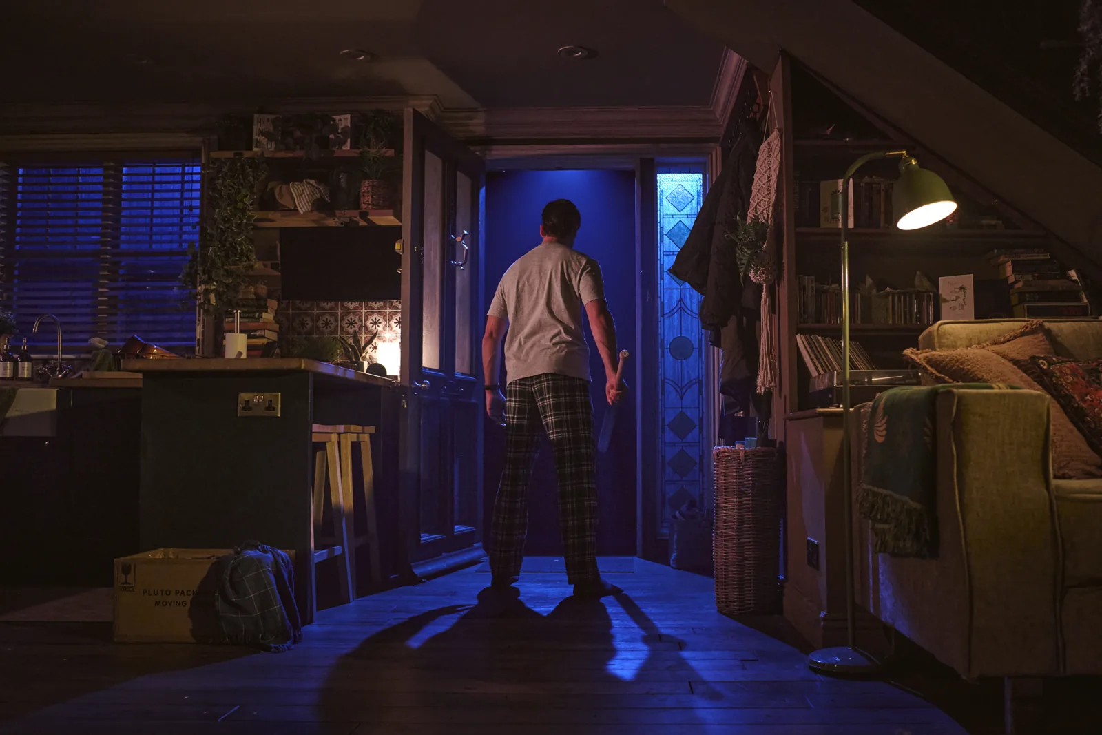 A man in pyjamas faces a glowing blue doorway in Paranormal Activity, Ambassadors Theatre
