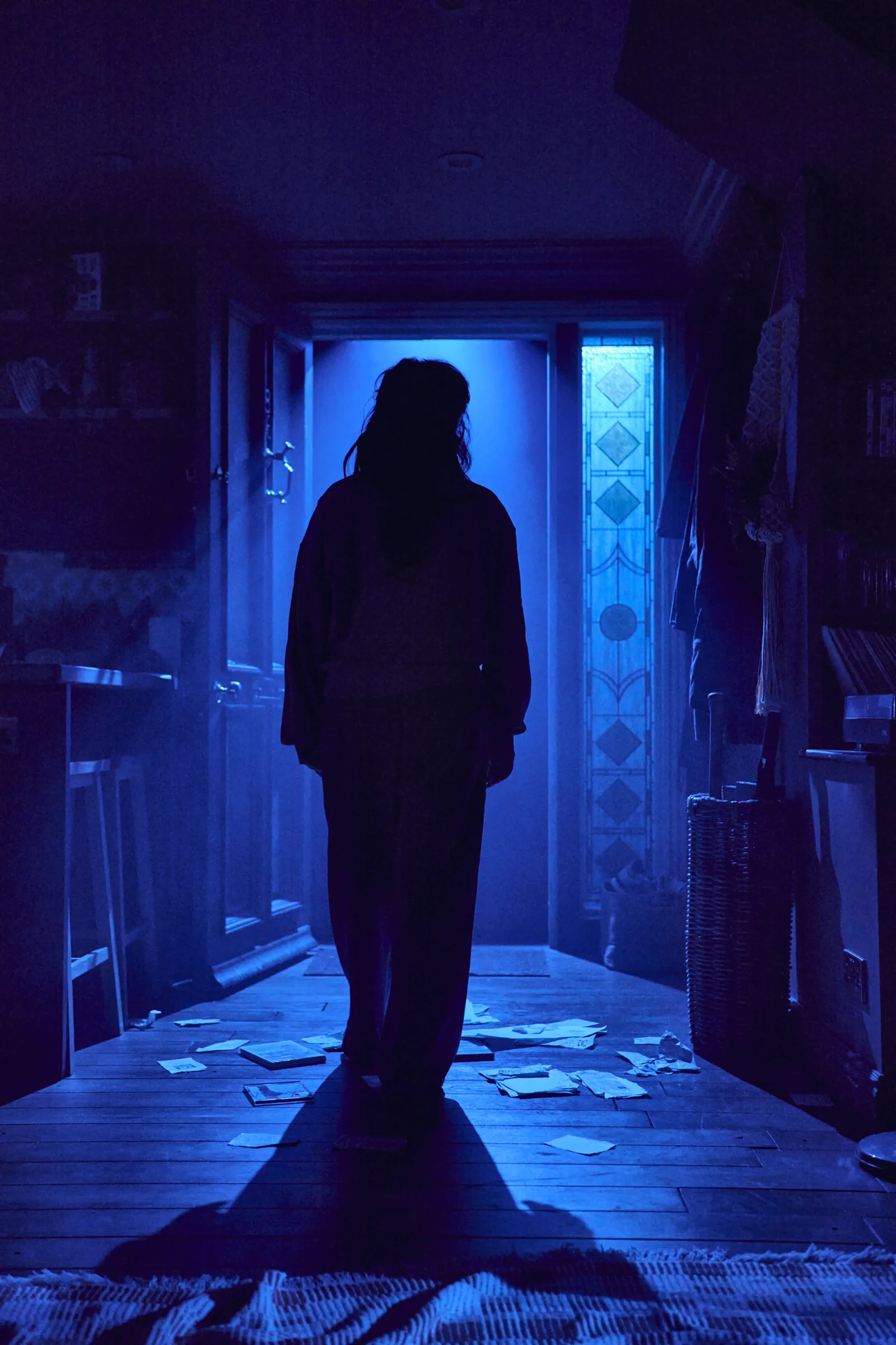 A silhouette stands in a hallway flooded with blue light in Paranormal Activity, Ambassadors Theatre