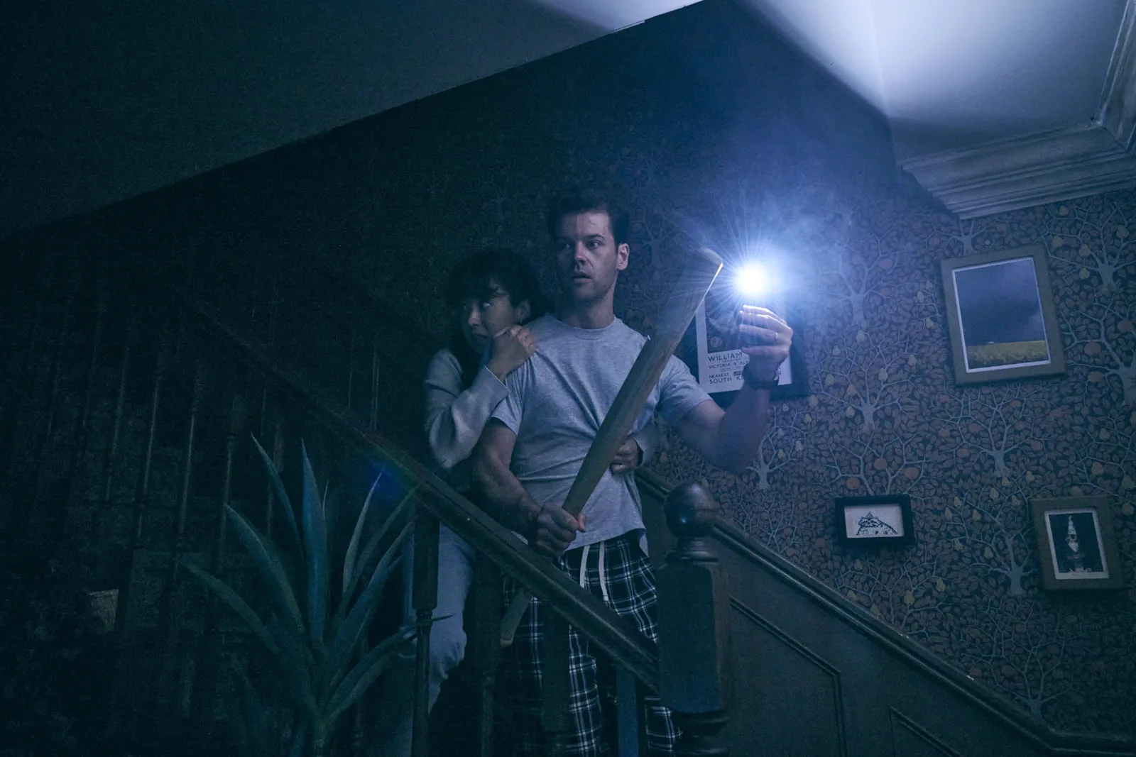 A man with a torch and bat creeps downstairs in Paranormal Activity, Ambassadors Theatre