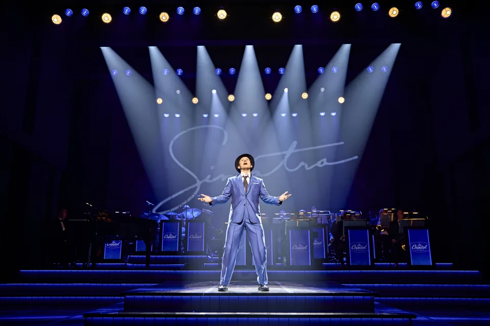 Joel Harper-Jackson as Frank Sinatra sings under spotlights in Sinatra The Musical, Aldwych Theatre