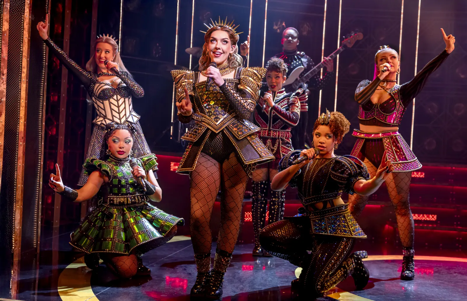 The queens strike a pose with microphones in red light, SIX at the Vaudeville Theatre