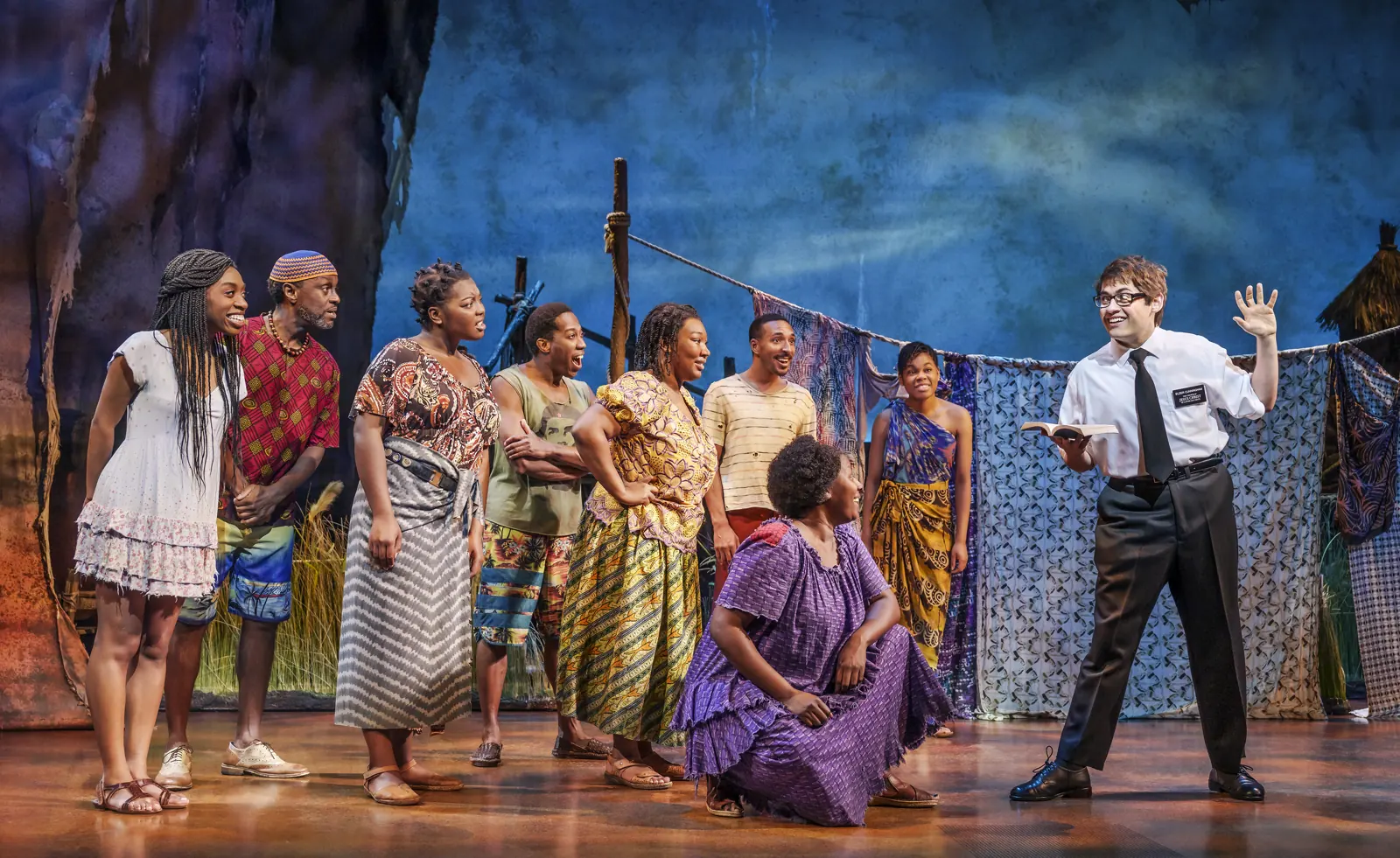A missionary with a book addresses villagers, The Book of Mormon, Prince of Wales Theatre