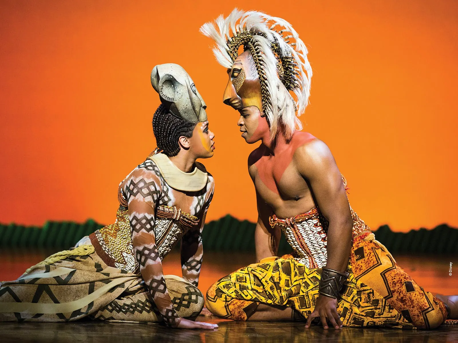 Two performers in lion headpieces kneel face to face, The Lion King, Lyceum Theatre