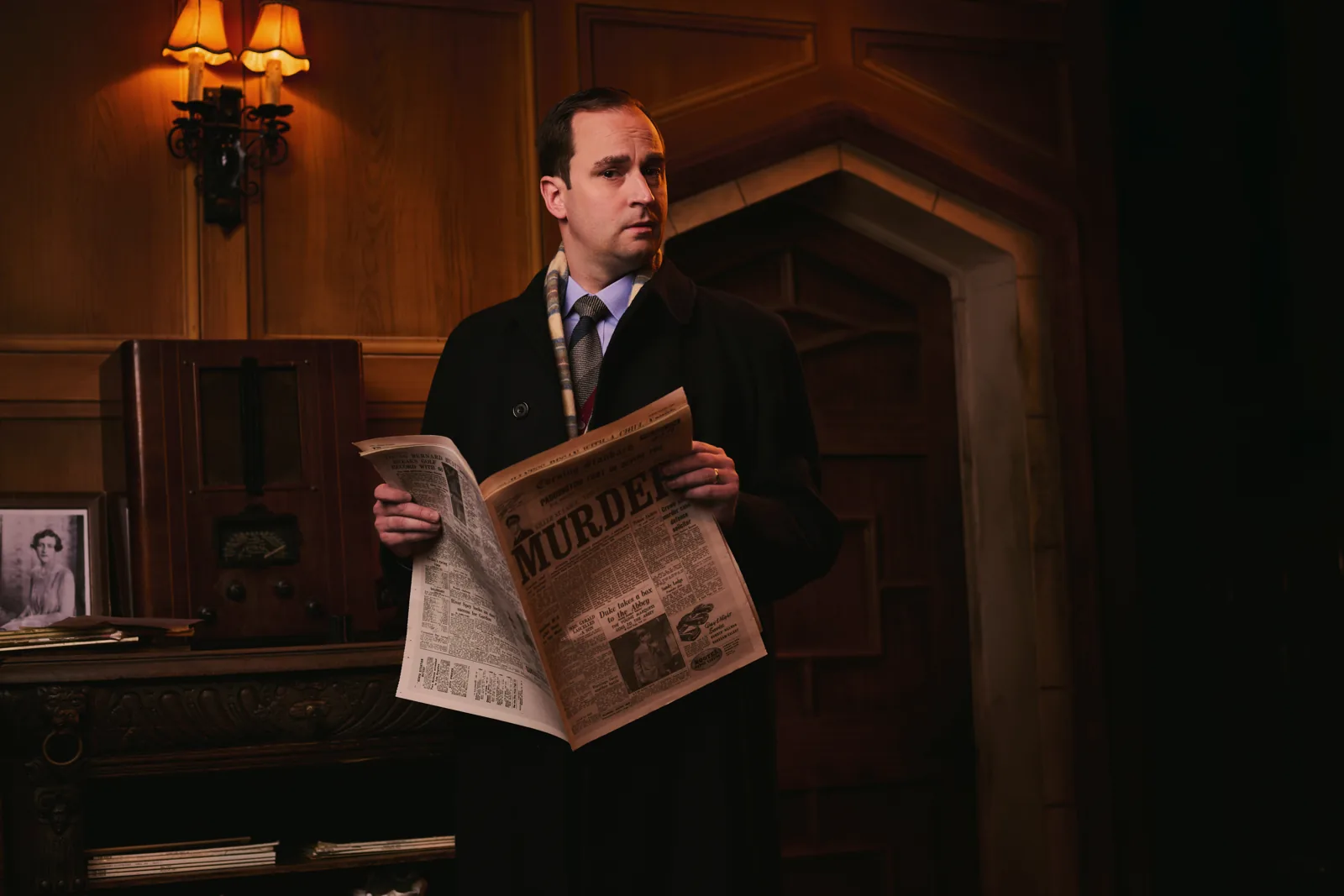 Ben Riddle as Giles Ralston with the newspaper in The Mousetrap at St Martin's Theatre
