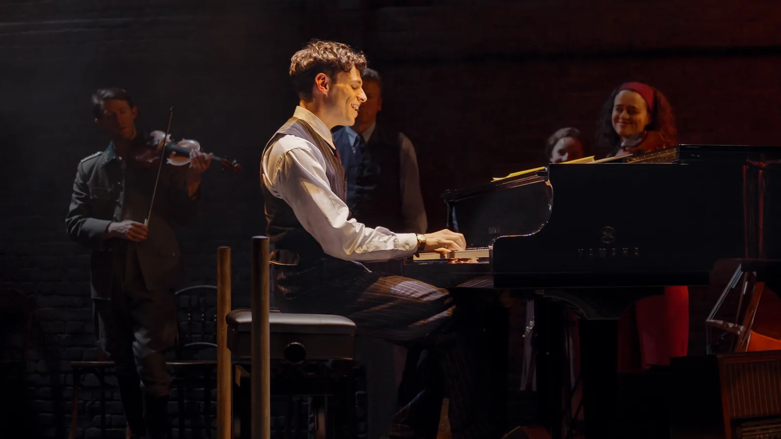 Daniel Krikler as Wladyslaw Szpilman plays the piano beside a violinist, The Pianist, Park Theatre