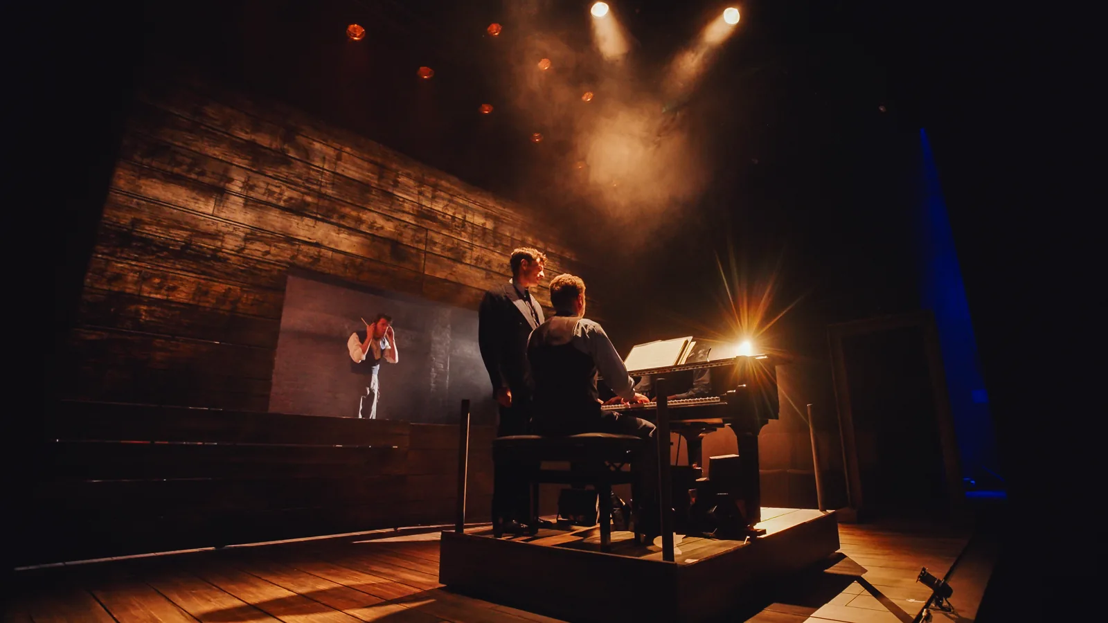 Two performers at a grand piano under warm spotlights in The Pianist, Park Theatre