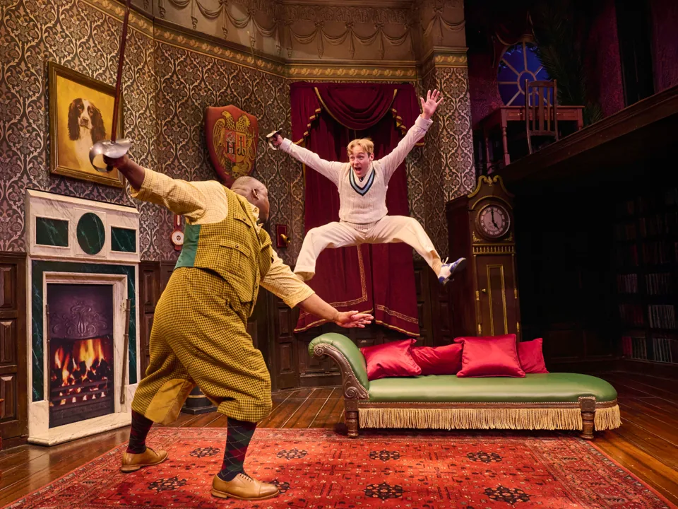 A man leaps mid sword fight in The Play That Goes Wrong, Duchess Theatre