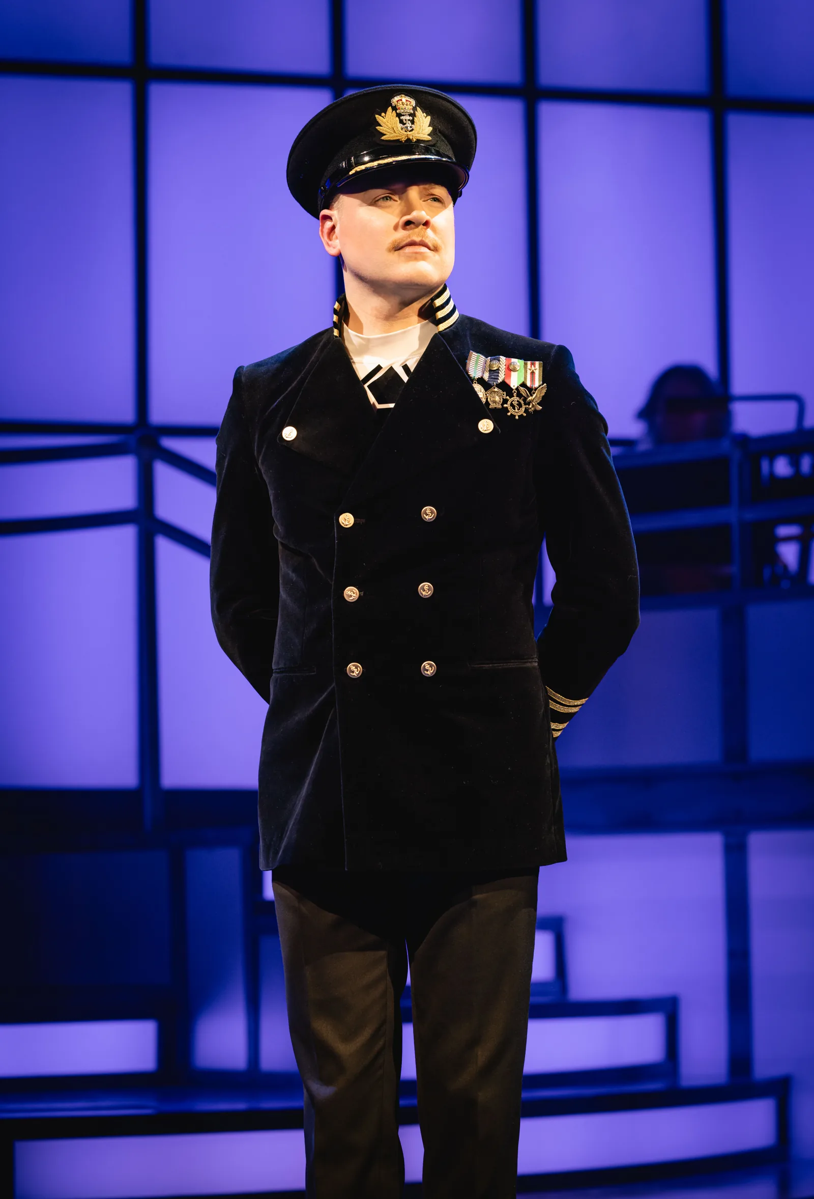 A performer in naval dress uniform under blue light: Titanique, Criterion Theatre