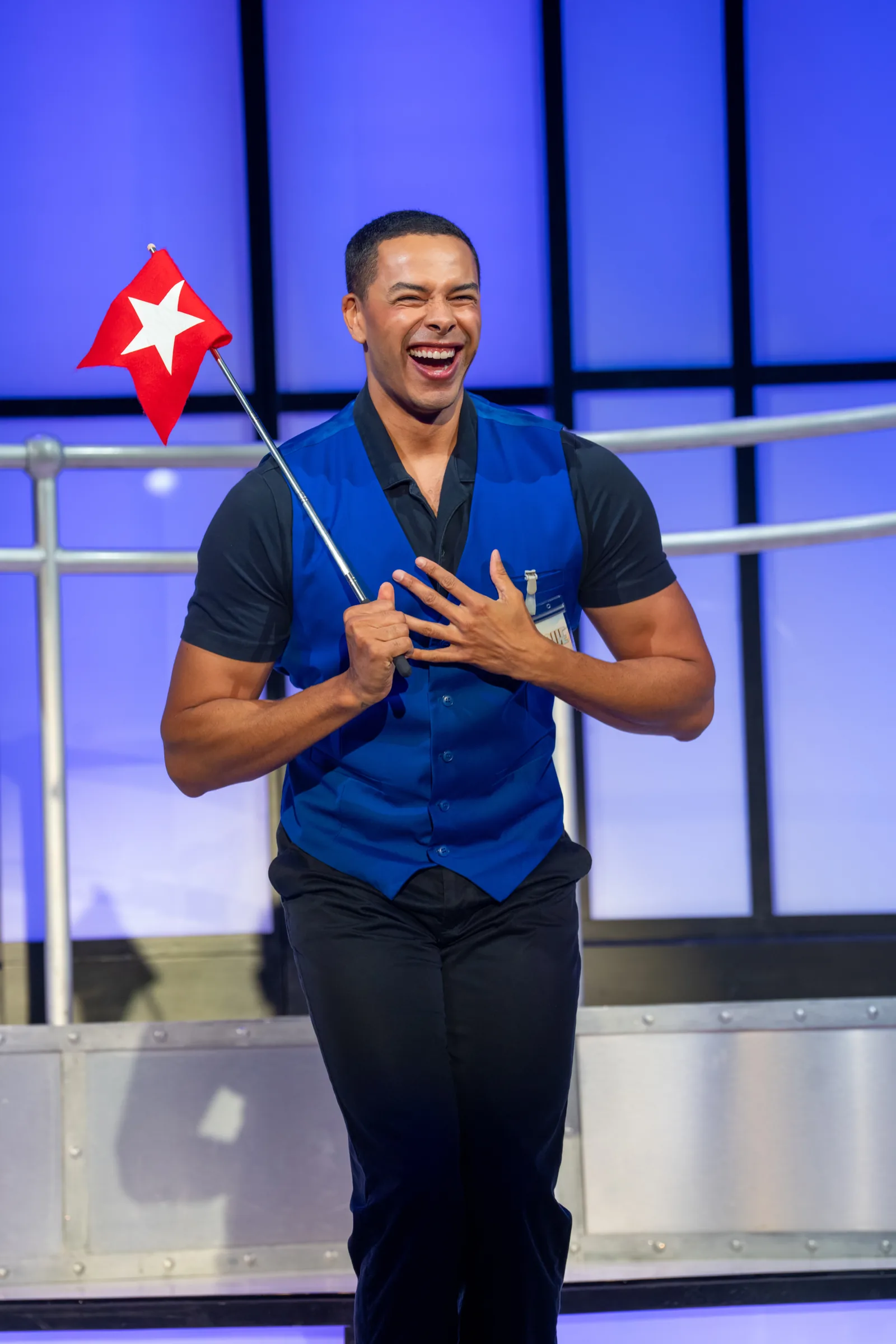 A laughing performer waves a red star flag in Titanique, Criterion Theatre