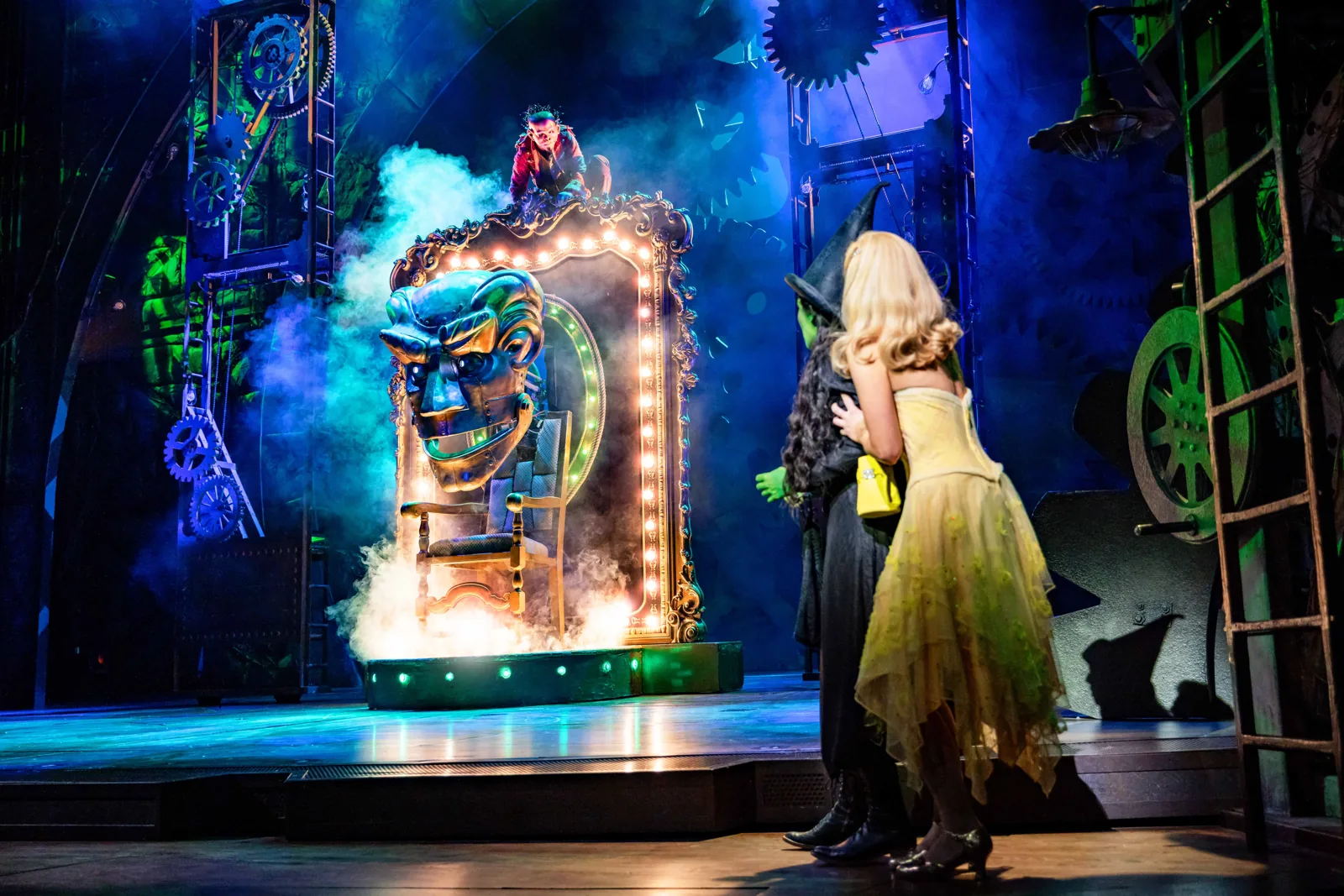 Emma Kingston and Zizi Strallen face the Wizard's giant head, Wicked, Apollo Victoria Theatre