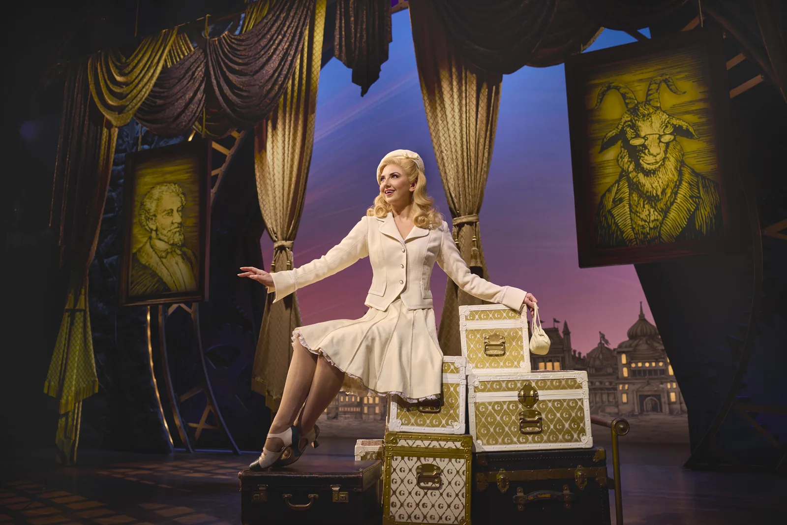 Zizi Strallen as Glinda sits on luggage trunks in Wicked, Apollo Victoria Theatre