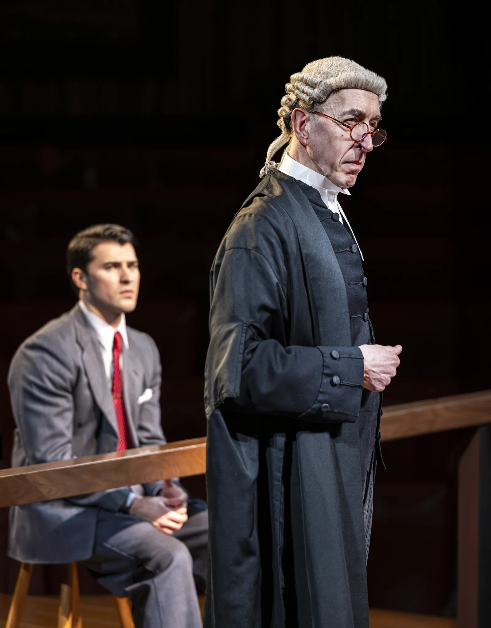 A bespectacled barrister beside a young man in grey: Witness for the Prosecution, County Hall